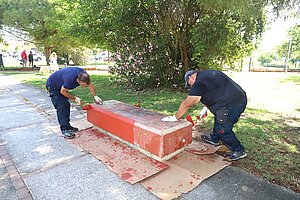 Trabajadores pintando bancos del parque